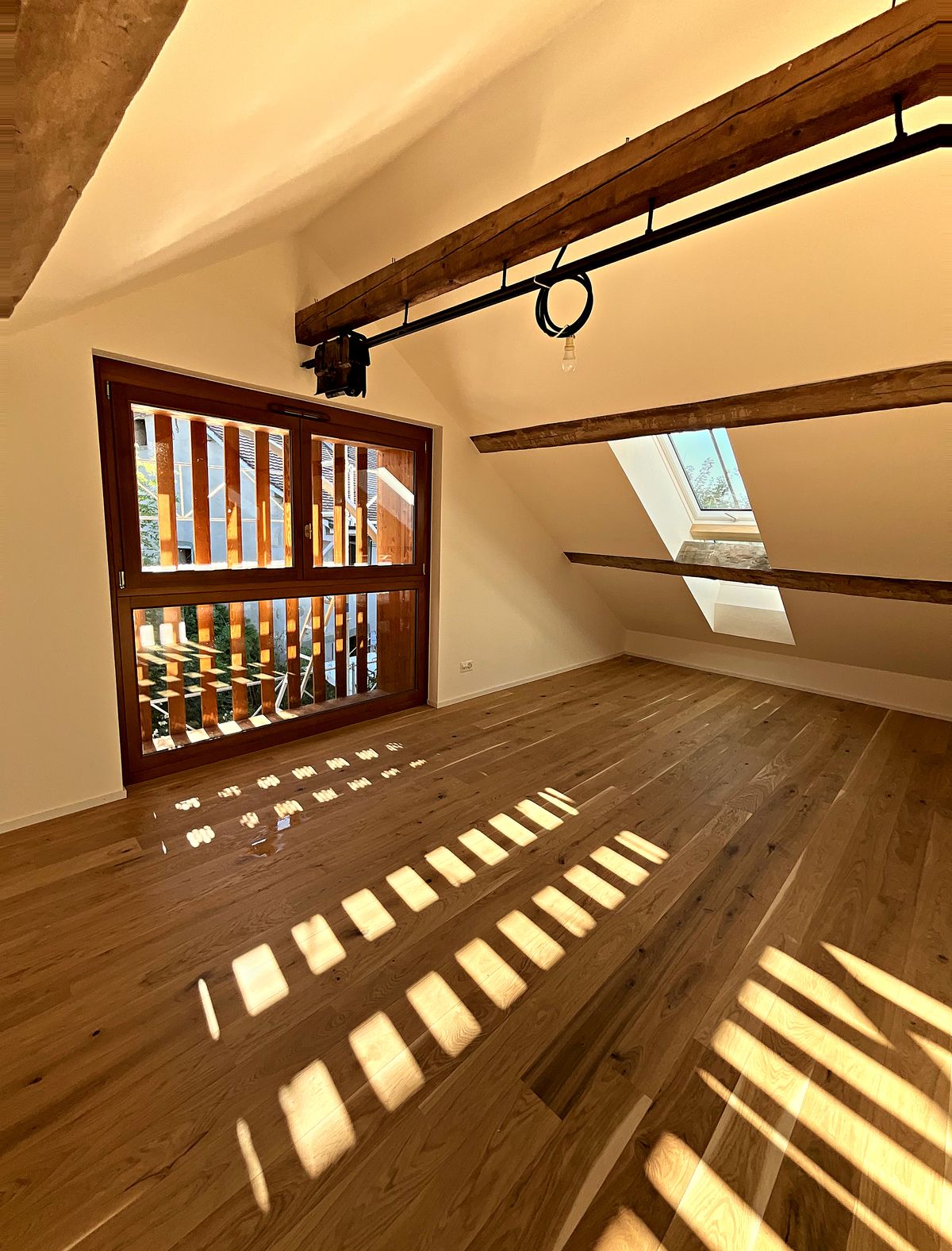 Pièce sous combles avec poutres apparentes et parquet